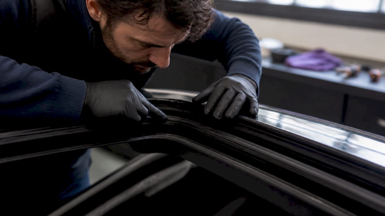 Ein Fachmann überprüft die Dichtung des Schiebedachs am Auto.